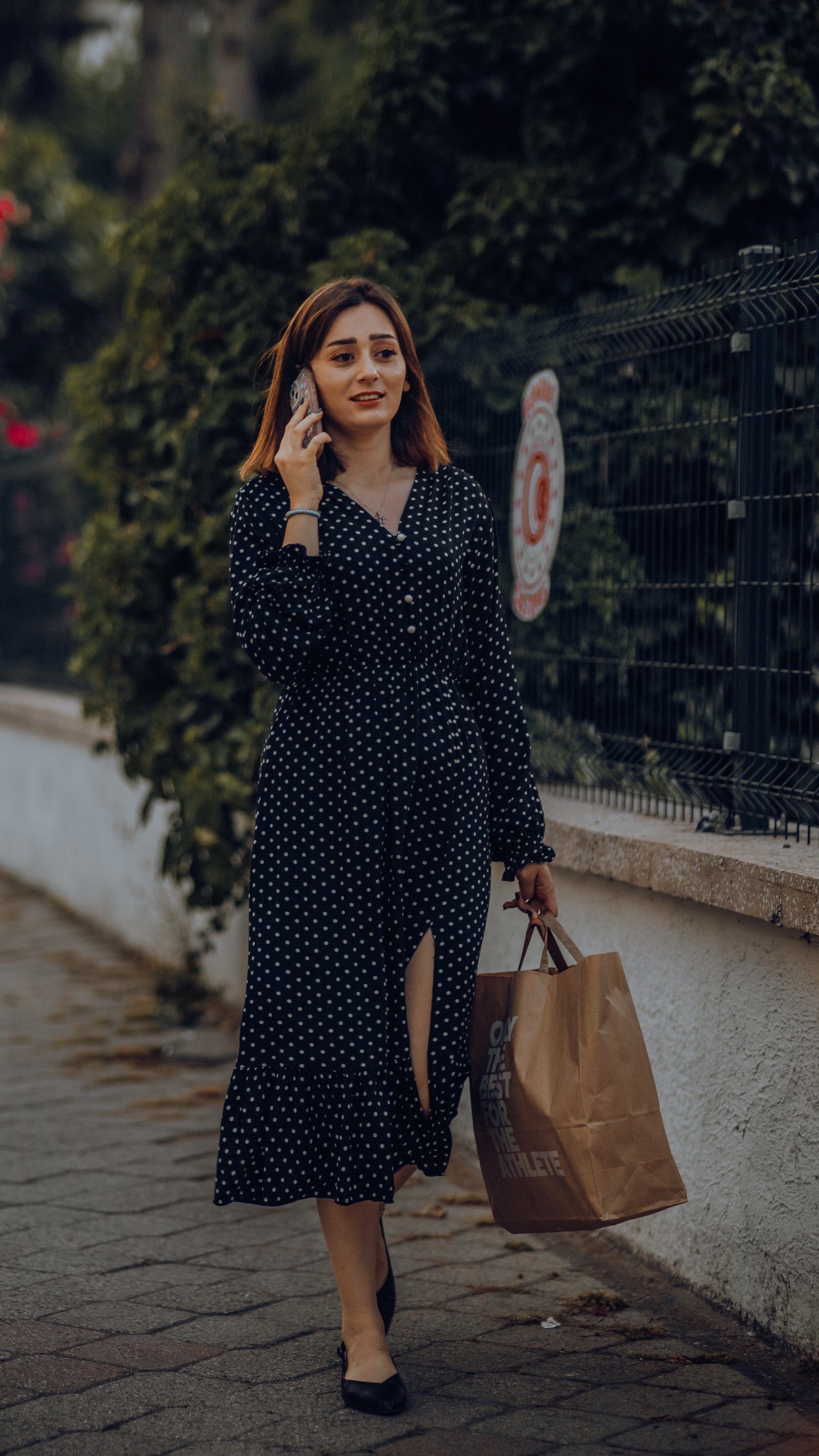 Young woman walking on a pavement talking on phone with Airtel connection.