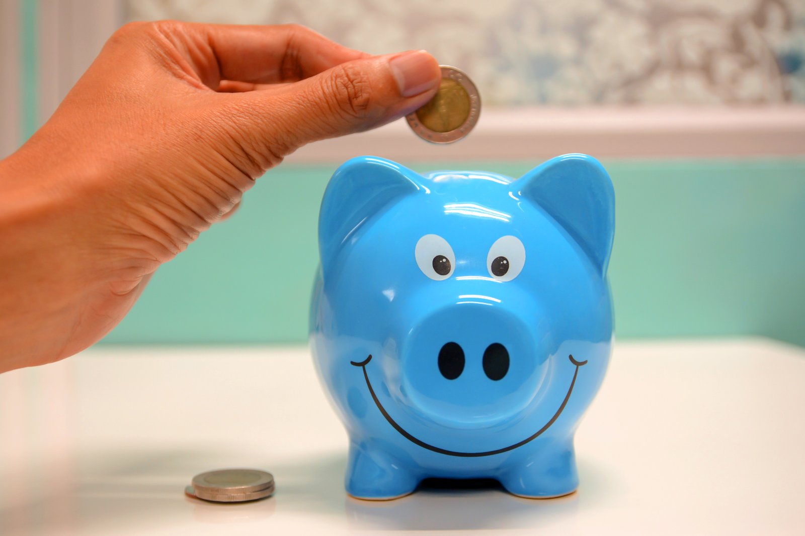 A person putting a coin in the piggy bank