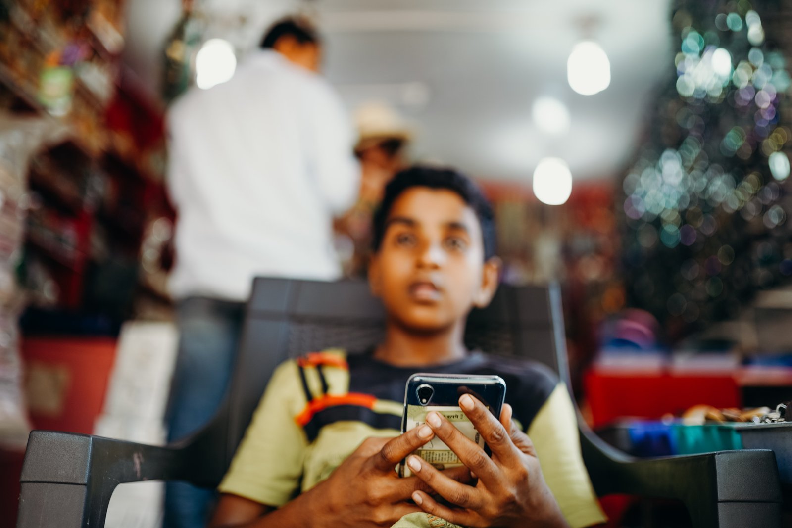 Person holding a Reliance India Jio smartphone inside an Indian shop.