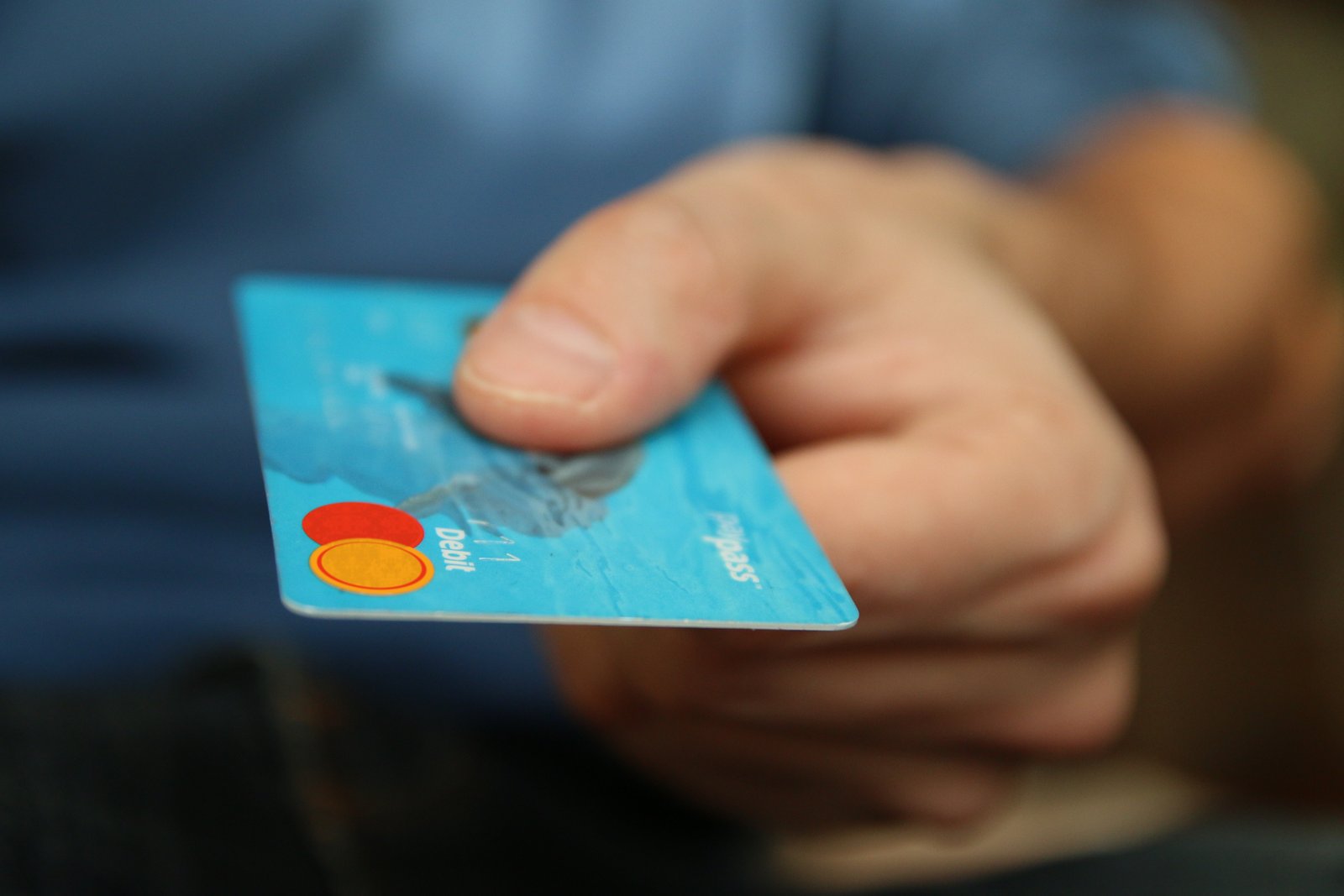 A man holding an SBI India credit card and giving it to a merchant to swipe for a purchase.