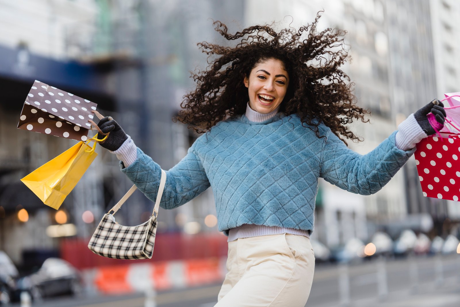 A happy Shopsy customer jumping in the air with shopping bags in hands.