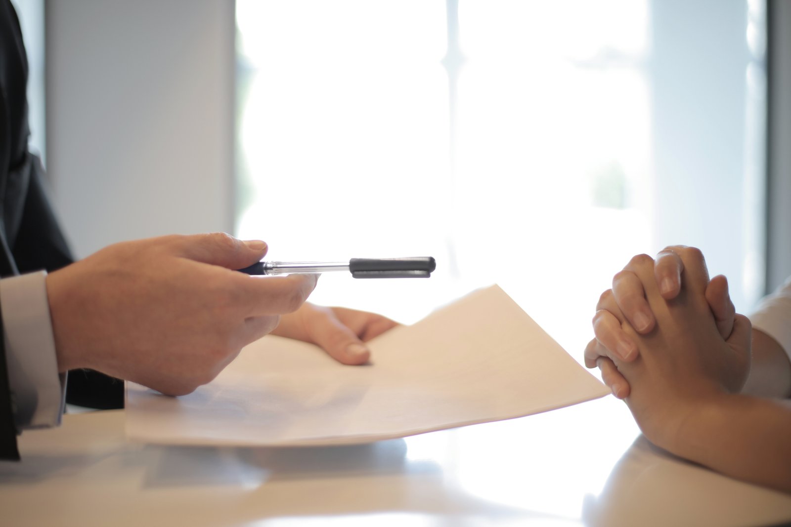 Bank representative offering a pen to a customer for loan application.