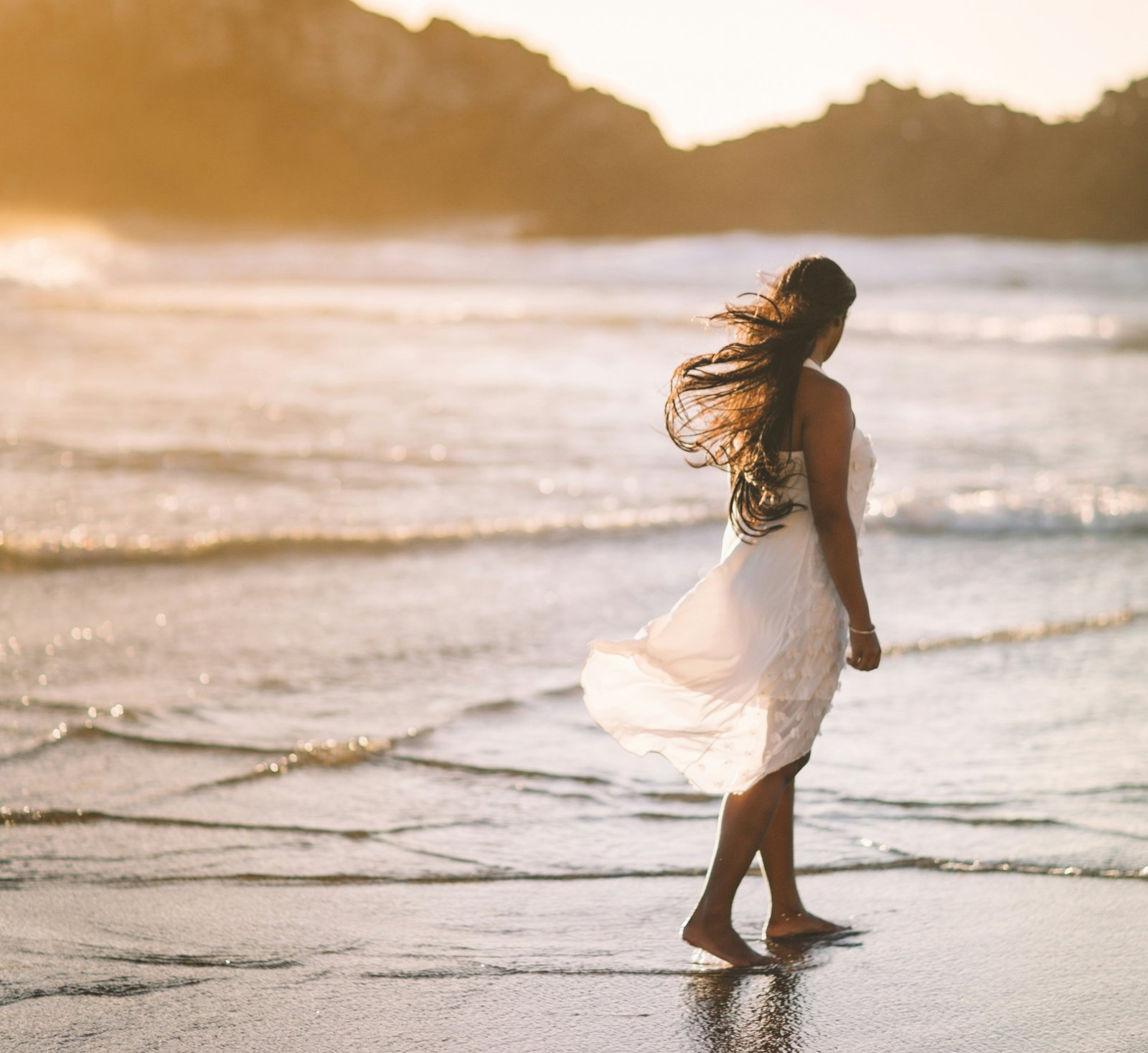 A girl walks on the beach while dealing while introspecting